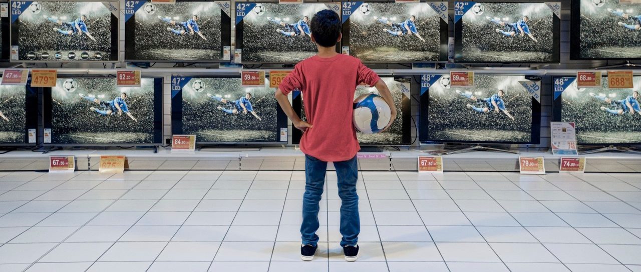 Back view of boy watching soccer in electronics store --- Image by © Hiya Images/Corbis