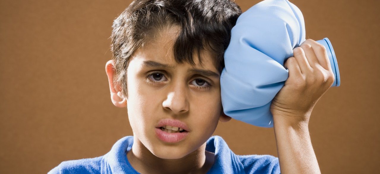 Boy holding ice pack to head --- Image by © Mike Kemp/Rubberball/Corbis