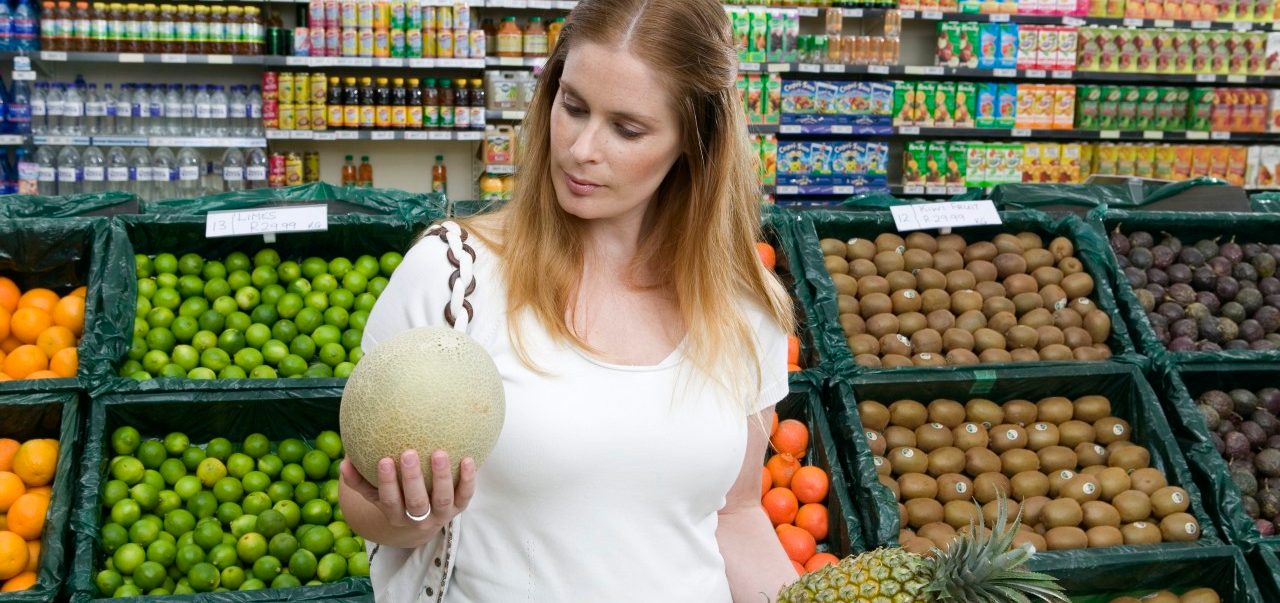 Woman holding melon and pineapple in supermarket --- Image by © 2/B2M Productions/Ocean/Corbis